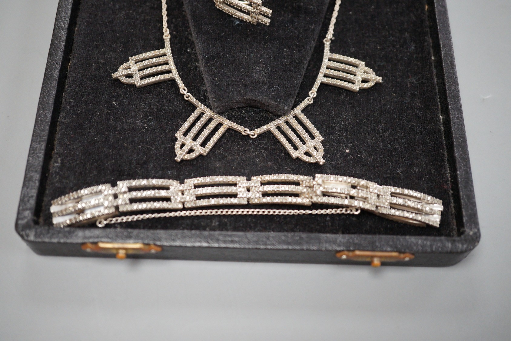 A stylish mid 20th century white metal and marcasite set parure, comprising a necklace, 42cm, bracelet, brooch and pair of ear clips.